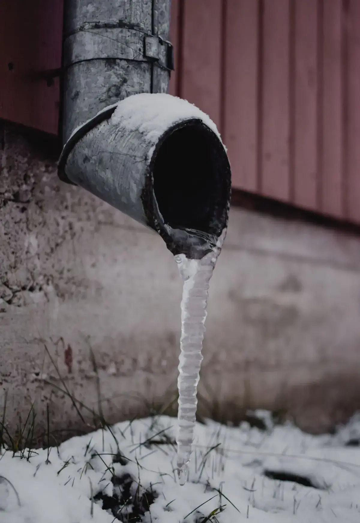 A frozen drain pipe with an icicle during a North Texas freeze
